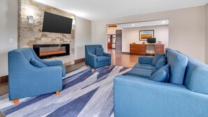 A modern living room with a stone accent wall, a flat-screen TV, a fireplace, and a blue sofa set. - Comfort Inn Somerset - Lake Cumberland (Somerset)
