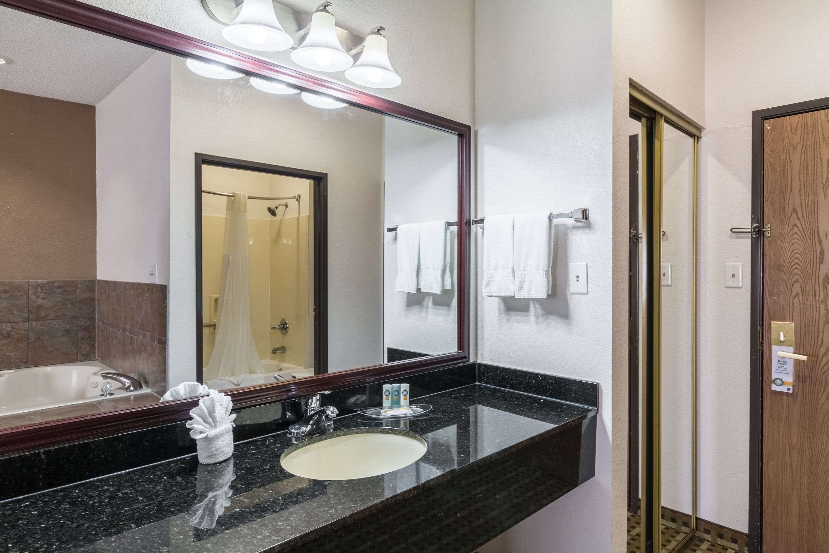 A hotel bathroom with a large mirror, a sink, a bathtub, and a shower.
