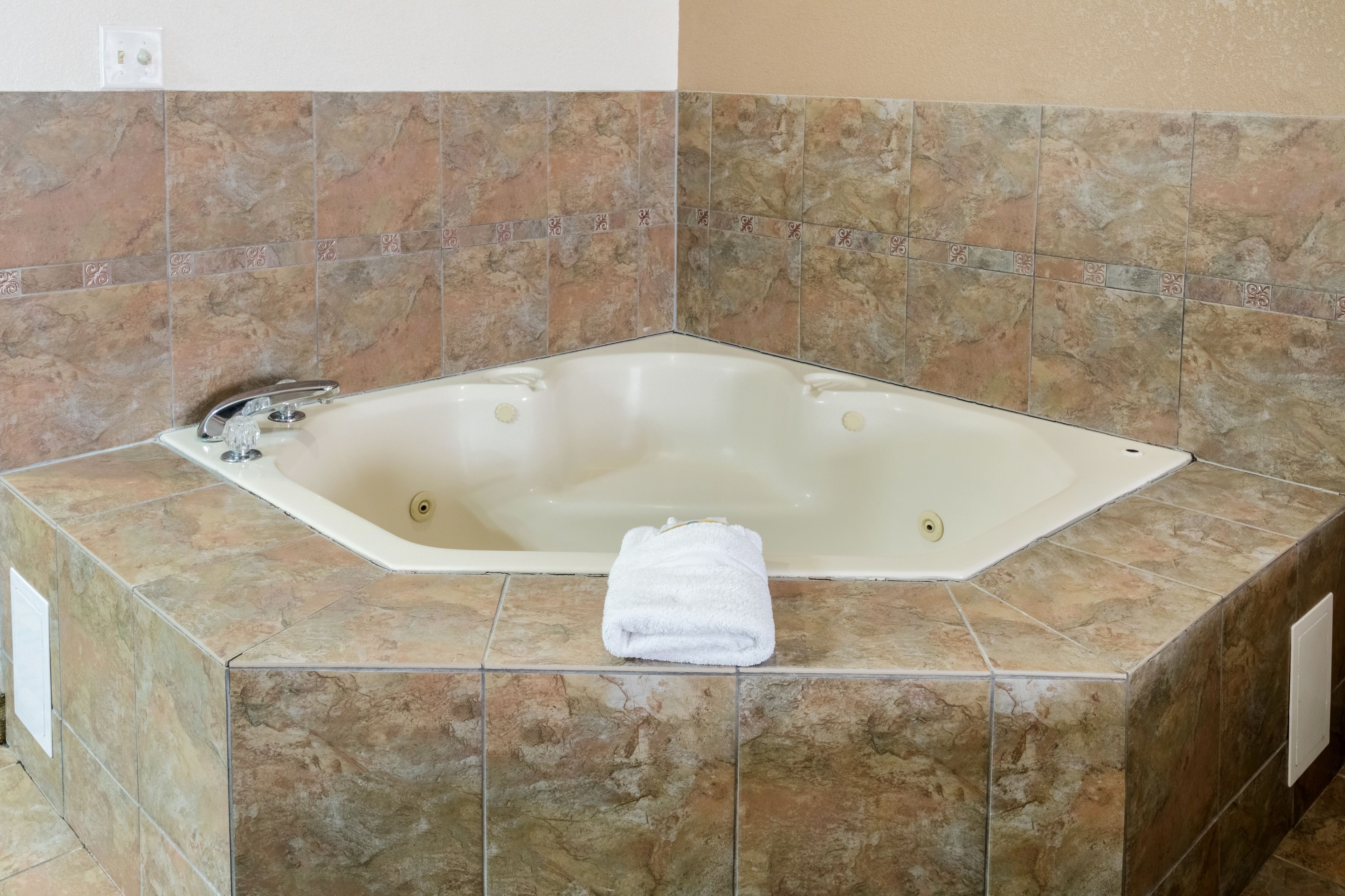 Un baño con una bañera independiente, una toalla y un muro cubierto de azulejos.