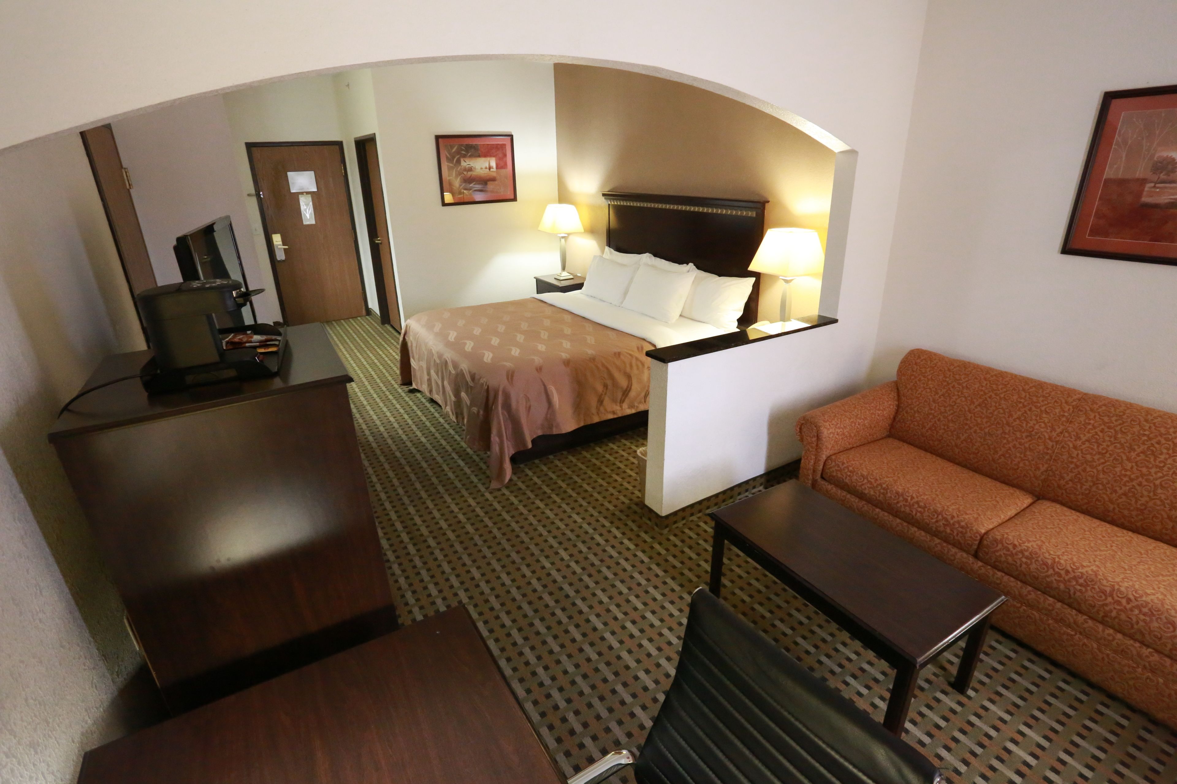 A hotel room with a bed, a desk, a sofa, and a TV.