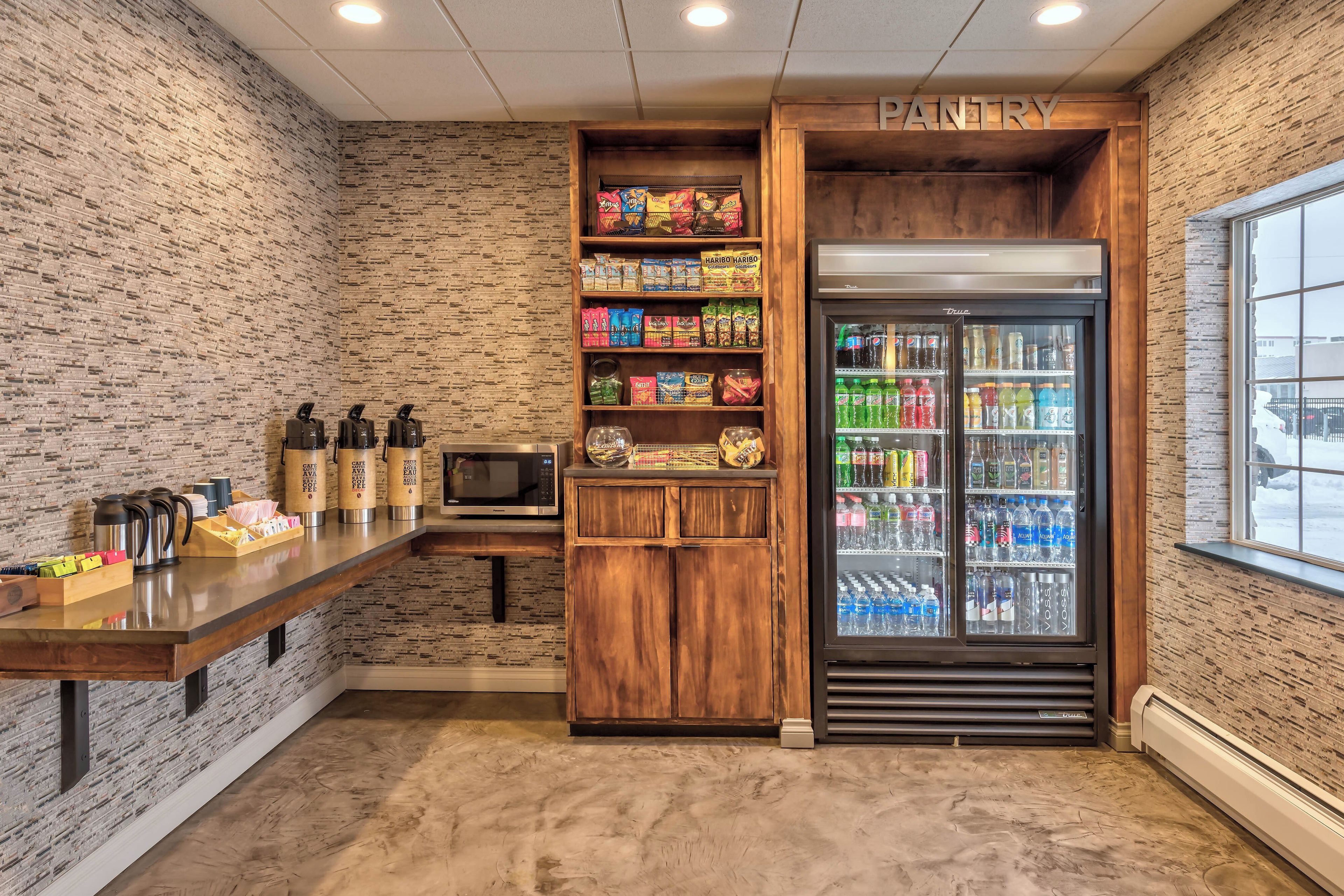 A kitchenette with a coffee station, snack shelves, and a beverage fridge.
