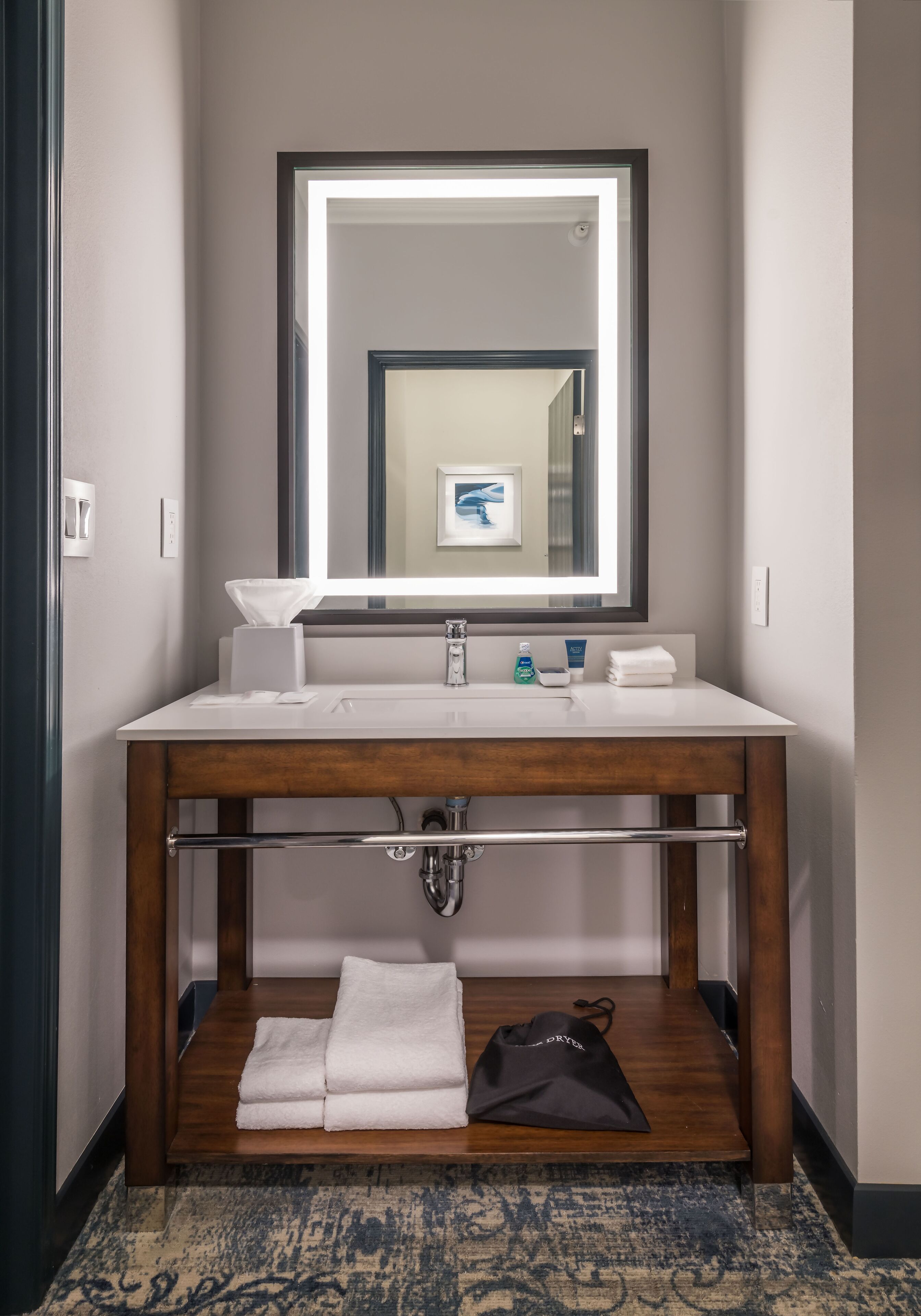 A bathroom with a wooden vanity, a large mirror, and a towel rack.