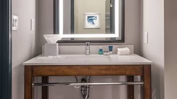 A bathroom with a wooden vanity, a large mirror, and a towel rack.