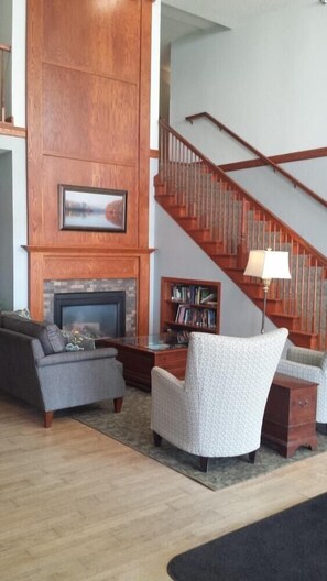 A living room with a fireplace, a staircase, and a bookshelf.