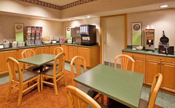Enjoy a convenient breakfast in this hotel room's breakfast area, featuring a counter with a coffee machine, waffle maker, and beverage dispenser.