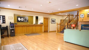 A hotel lobby with a wooden reception desk, a reception area, a staircase, and a fireplace. - Country Inn & Suites by Radisson, Bloomington-Normal West, IL (Bloomington)