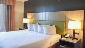 A hotel room with a large bed, two bedside lamps, a nightstand with a phone, and a headboard with vertical wooden panels.