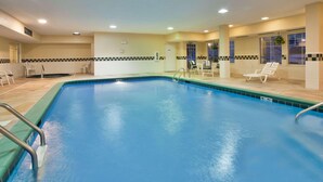 An indoor swimming pool with clear blue water, surrounded by lounge chairs and a small seating area. - Country Inn & Suites by Radisson, Bloomington-Normal West, IL (Bloomington)