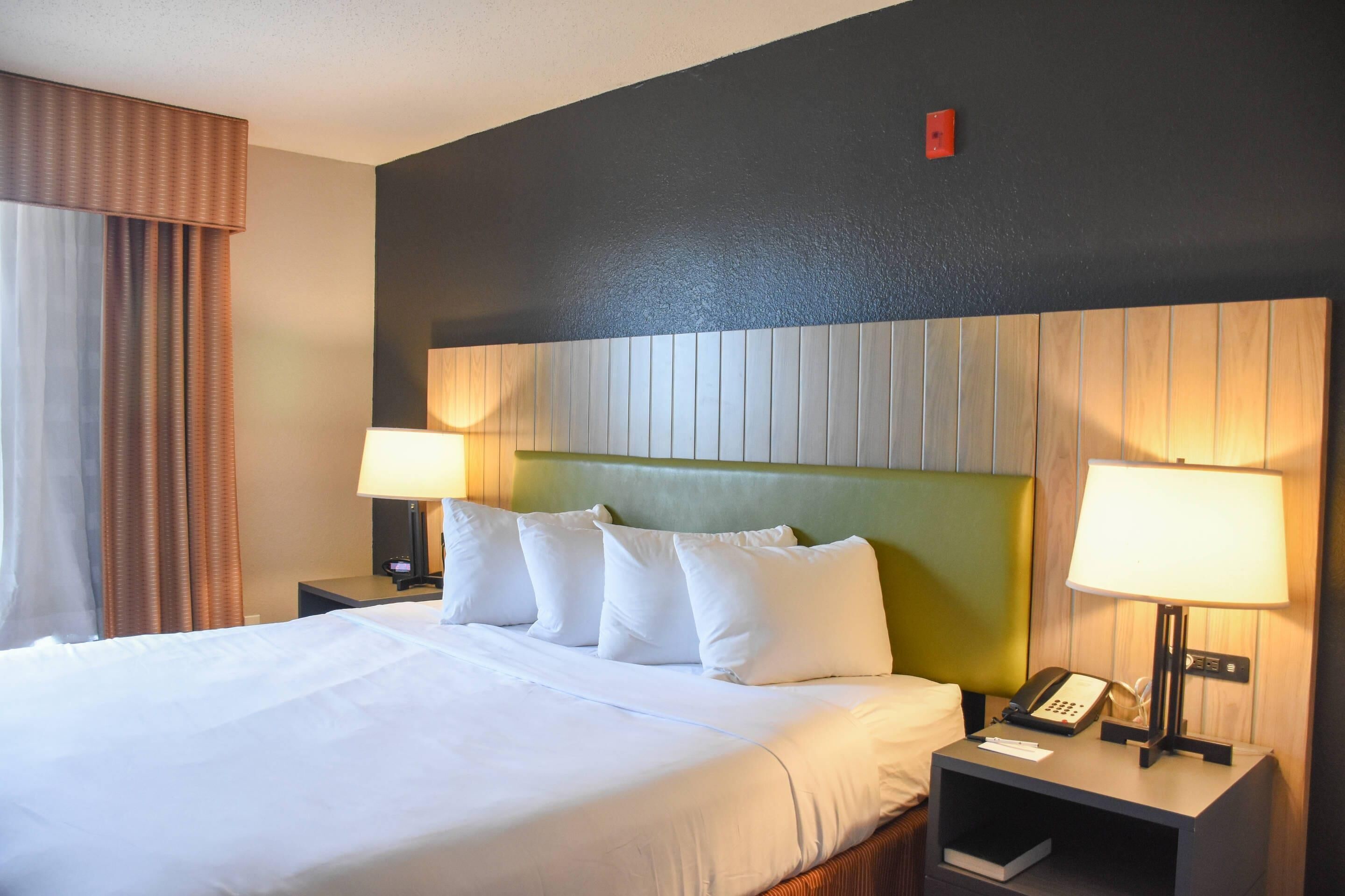 Habitación de hotel con una cama grande, dos mesitas de noche, un teléfono y una lámpara a cada lado.