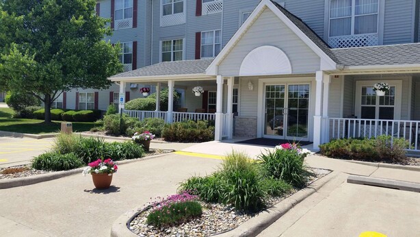 A hotel entrance with a covered porch, a parking lot, and landscaped gardens. - Country Inn & Suites by Radisson, Bloomington-Normal West, IL (Bloomington)