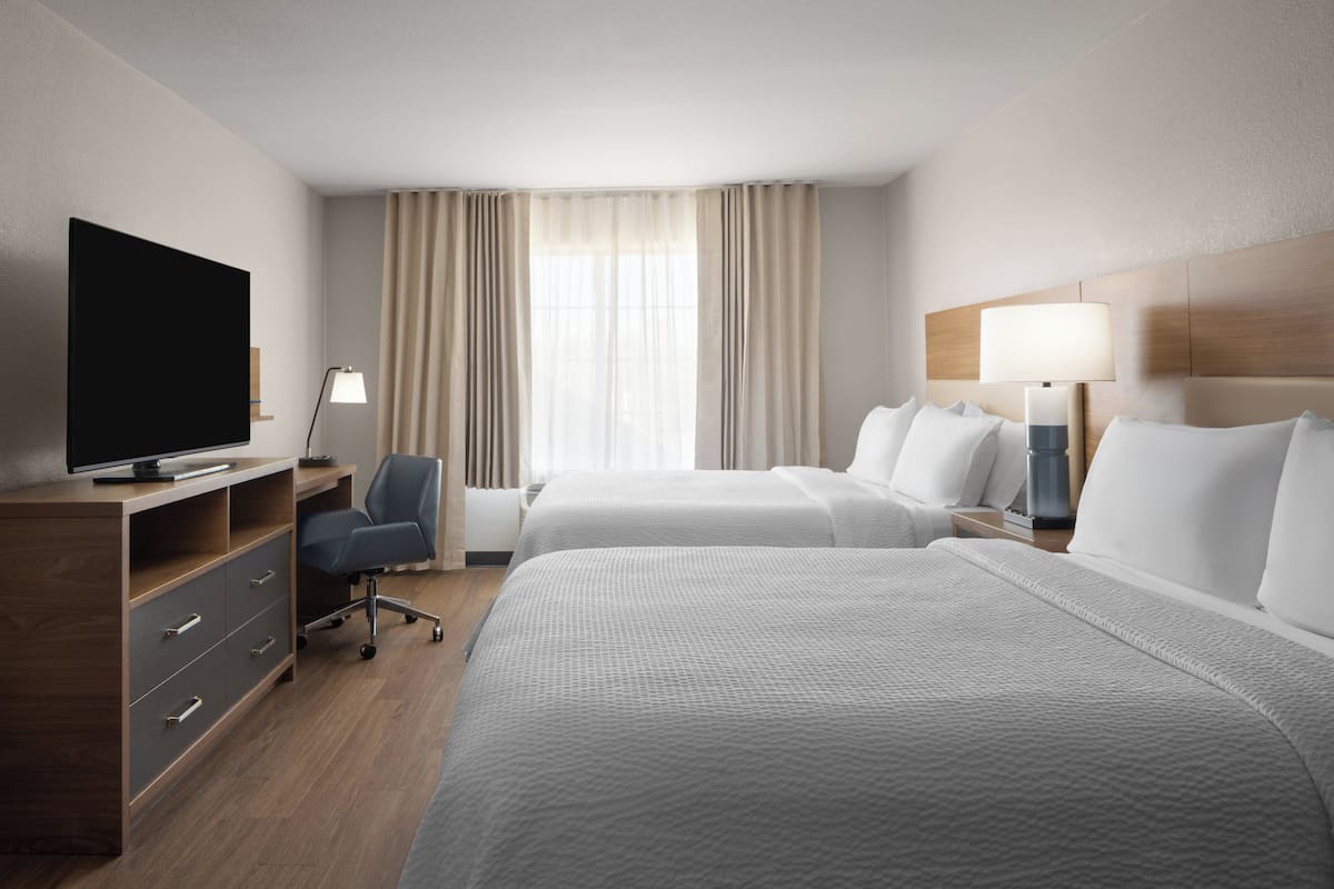 Une chambre d’hôtel avec deux lits, un bureau avec une télévision et une lampe.