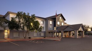 A hotel with a modern design, featuring a large entrance with a covered area, multiple windows, and an American flag. - Garner Hotel Phoenix Northwest – Surprise by IHG (Surprise)