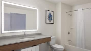 Un baño moderno con un espejo grande, un lavamanos, un inodoro y una bañera.