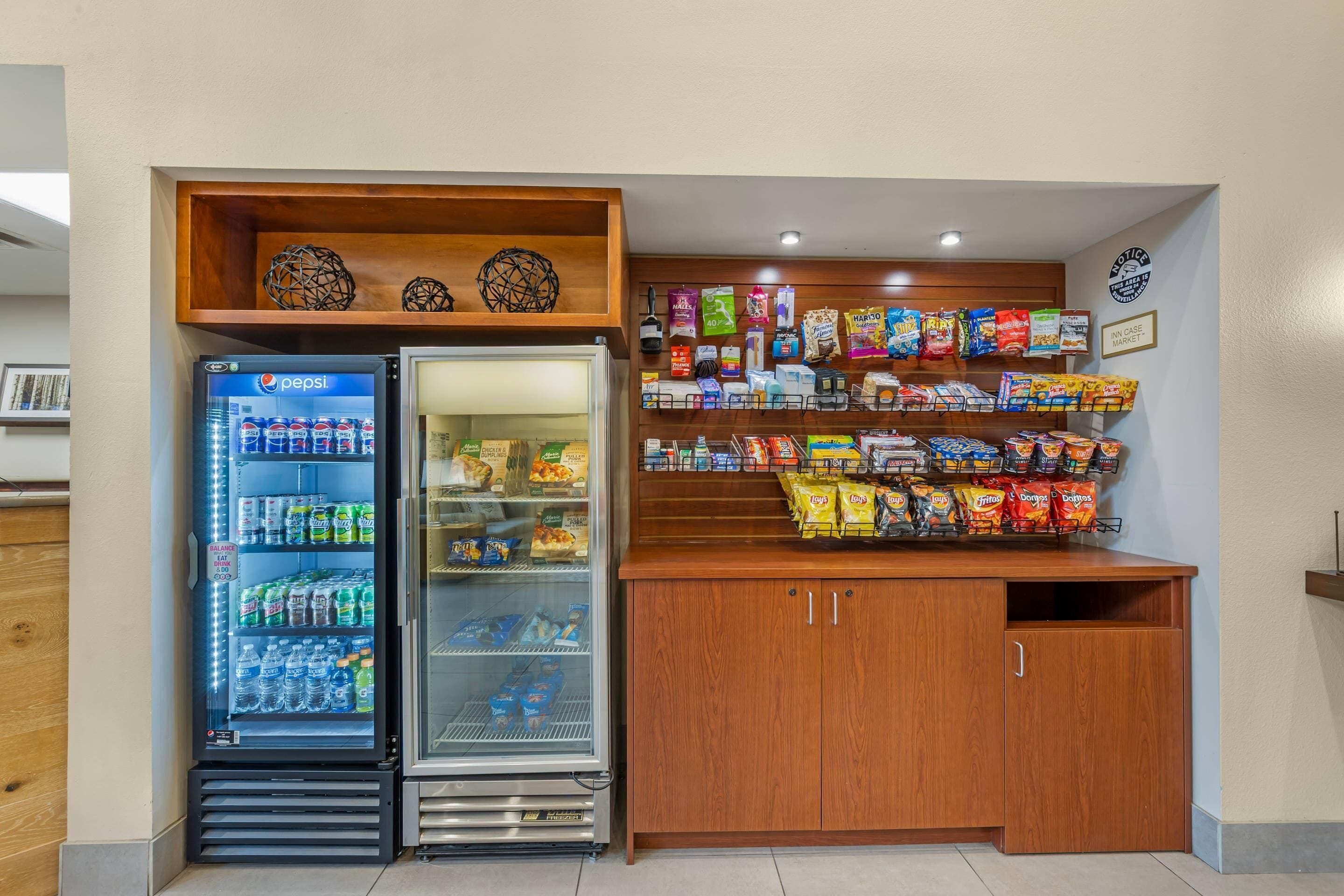 Zona de máquinas expendedoras con aperitivos y un refrigerador de Pepsi.