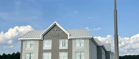 A Country Inn & Suites building with a prominent sign, multiple windows, and a brick facade.