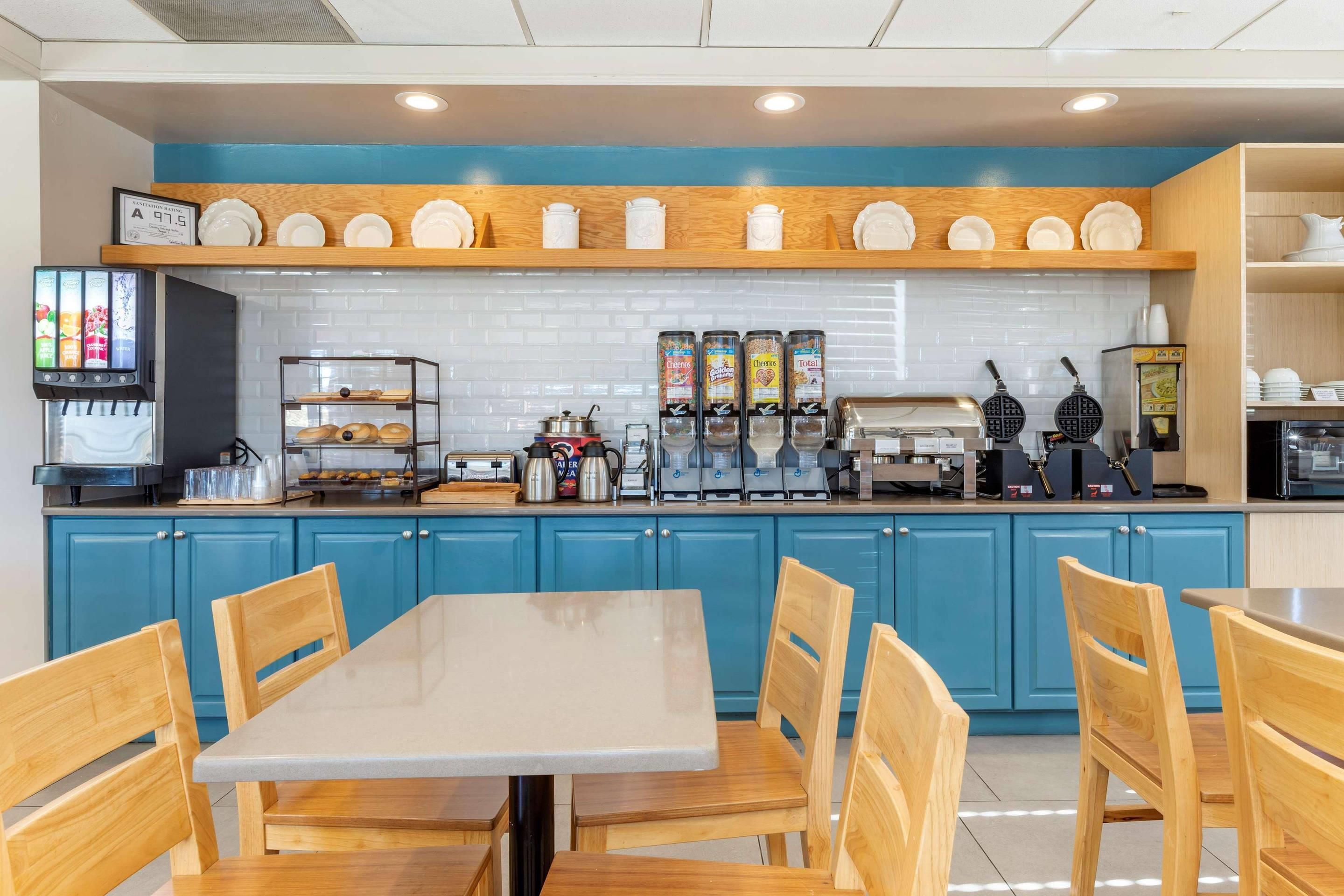 Un restaurante con una decoración azul y blanca, que ofrece una estación de bebidas de autoservicio, una máquina para gofres y una cafetera.