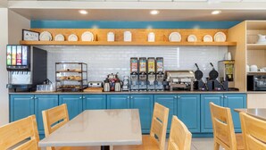 Ein Restaurant mit blauer und weißer Farbgestaltung, das eine Selbstbedienungsgetränkestation, einen Waffelautomaten und eine Kaffeemaschine bietet.