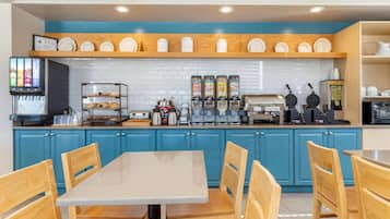 Un restaurante con una decoración azul y blanca, que ofrece una estación de bebidas de autoservicio, una máquina para gofres y una cafetera.