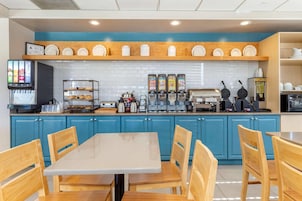 Un restaurante con una decoración azul y blanca, que ofrece una estación de bebidas de autoservicio, una máquina para gofres y una cafetera.