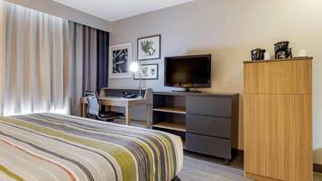 Una habitación de hotel con cama, escritorio, televisor y armario.