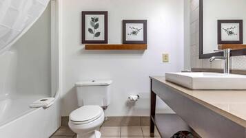A modern bathroom with a toilet, sink, and shower. There are framed botanical prints on the wall.