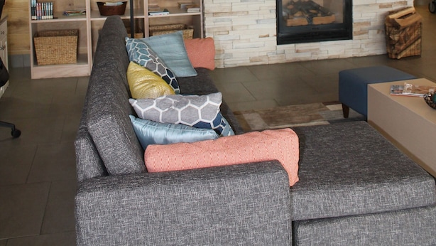 A living room with a grey sofa, a bookshelf, a fireplace, and a clock on the wall. - Country Inn & Suites by Radisson, Lumberton, NC (Lumberton)