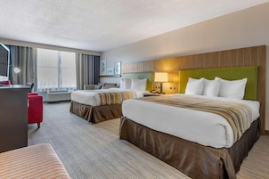 Habitación de hotel con dos camas, un escritorio, una silla y un ventanal grande.