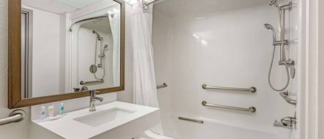 A bathroom with a white sink, mirror, and bathtub.