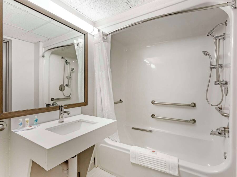 A bathroom with a white sink, mirror, and bathtub.