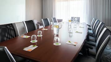 Un salón de conferencias con una larga mesa, sillas y una pantalla para proyector.