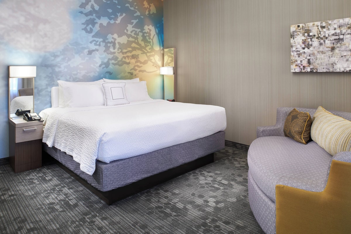 Ein Hotelzimmer mit Bett, Schlafsofa, Nachttisch und Lampe.