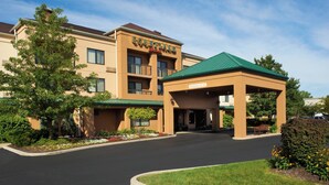 A Courtyard Inn with a covered entrance, a landscaped driveway, and a clear sky. - Courtyard by Marriott Toledo Maumee/Arrowhead (Maumee)
