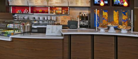 A modern cafe with a wooden counter, menu boards, and a coffee machine.