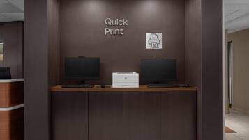 A reception desk with two monitors, a printer, and a sign reading "Quick Print".
