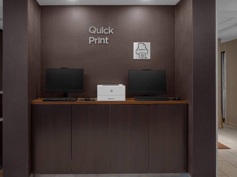 A reception desk with two monitors, a printer, and a sign reading "Quick Print".