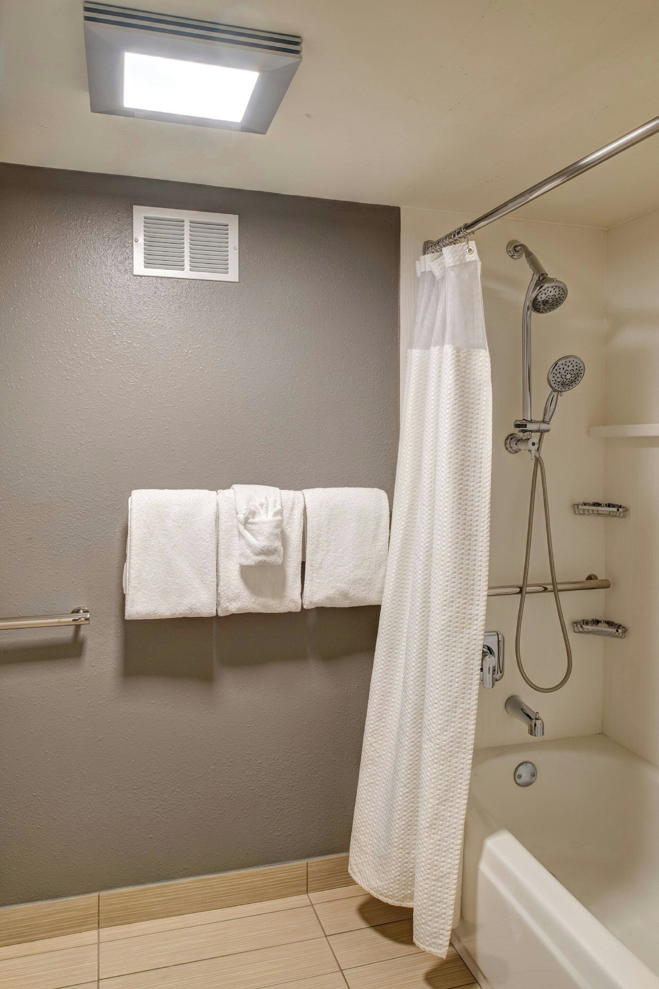 A bathroom with a bathtub, shower, and a towel rack with towels.