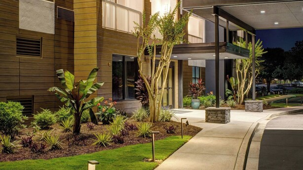 Een Courtyard by Marriott hotel met een moderne gevel, een terras en verzorgde beplanting.