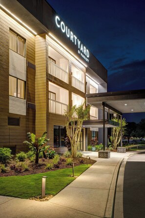 Un hotel Courtyard by Marriott con fachada moderna, zona de estar al aire libre y jardines bien cuidados.