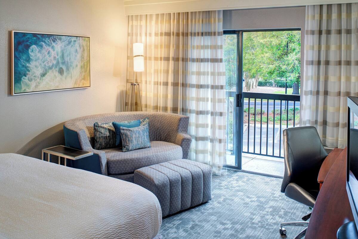 Une chambre d’hôtel avec un grand lit, un canapé, un bureau et une vue sur l’extérieur.
