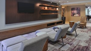 Een moderne woonkamer met een flatscreen televisie, houten planken en comfortabele zitmogelijkheden.