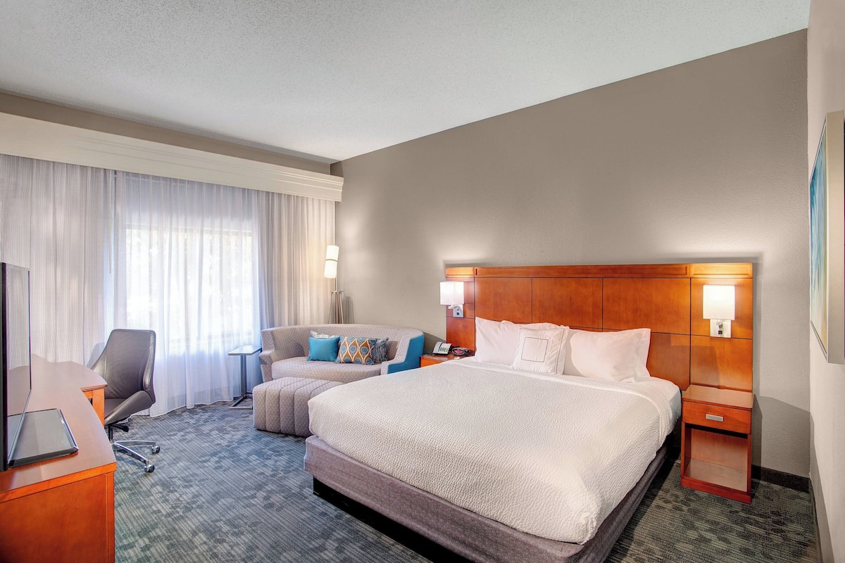 Une chambre d’hôtel avec un grand lit, un bureau, une chaise et un canapé.