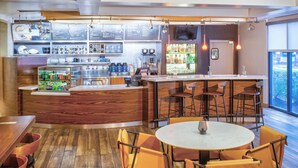 Een restaurant met een bar, houten vloer en oranje stoelen.