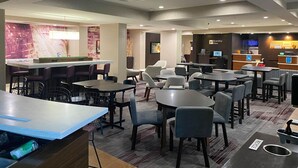 Un moderno vestíbulo de hotel con zona de bar, arreglos de asientos y un mostrador de recepción.