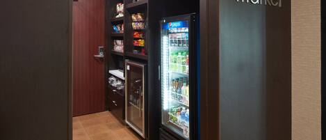 A vending machine area with a Pepsi refrigerator and shelves stocked with snacks and beverages.
