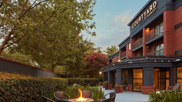 Un patio con un pozo de fuego, asientos exteriores y un edificio del hotel Marriott al fondo.