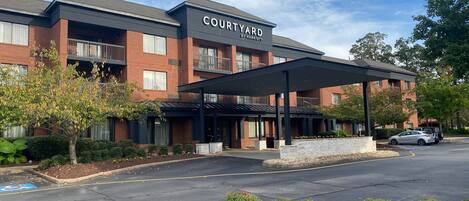 A Courtyard by Marriott hotel with a covered entrance, brick facade, and parking area.