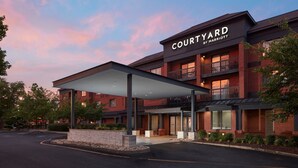 Un hotel Courtyard by Marriott con entrada cubierta, fachada de ladrillo y varios balcones.