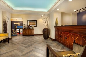 A hotel lobby with a herringbone floor pattern, a reception desk, a large vase, and a painting on the wall. - Comfort Inn Downtown DC/Convention Center (Washington)