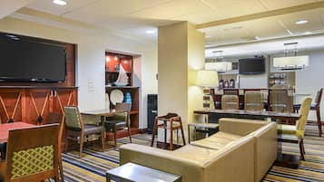 A hotel lobby with seating, a television, and a waste bin.