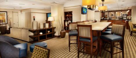 A hotel lobby with a seating area, a bar, and a reception desk.